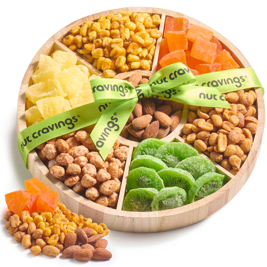 Round wooden tray of dried pineapple, papaya, kiwi, almonds, corn kernels and peanuts tied with a green ribbon